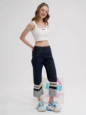 Female model wearing macaron blue mesh chunky dad sneakers with cuffed dark denim jeans in a minimalist studio streetwear look
