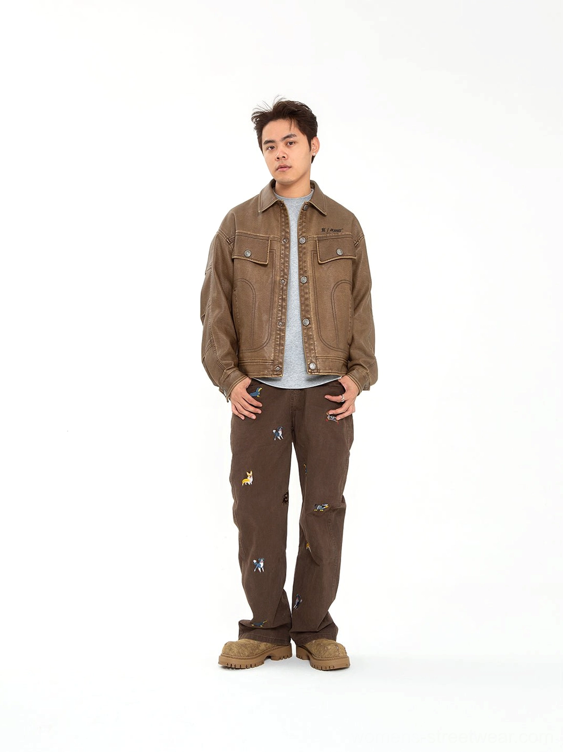 Male model wearing khaki platform combat boots with a brown denim jacket printed cargo pants and urban streetwear outfit