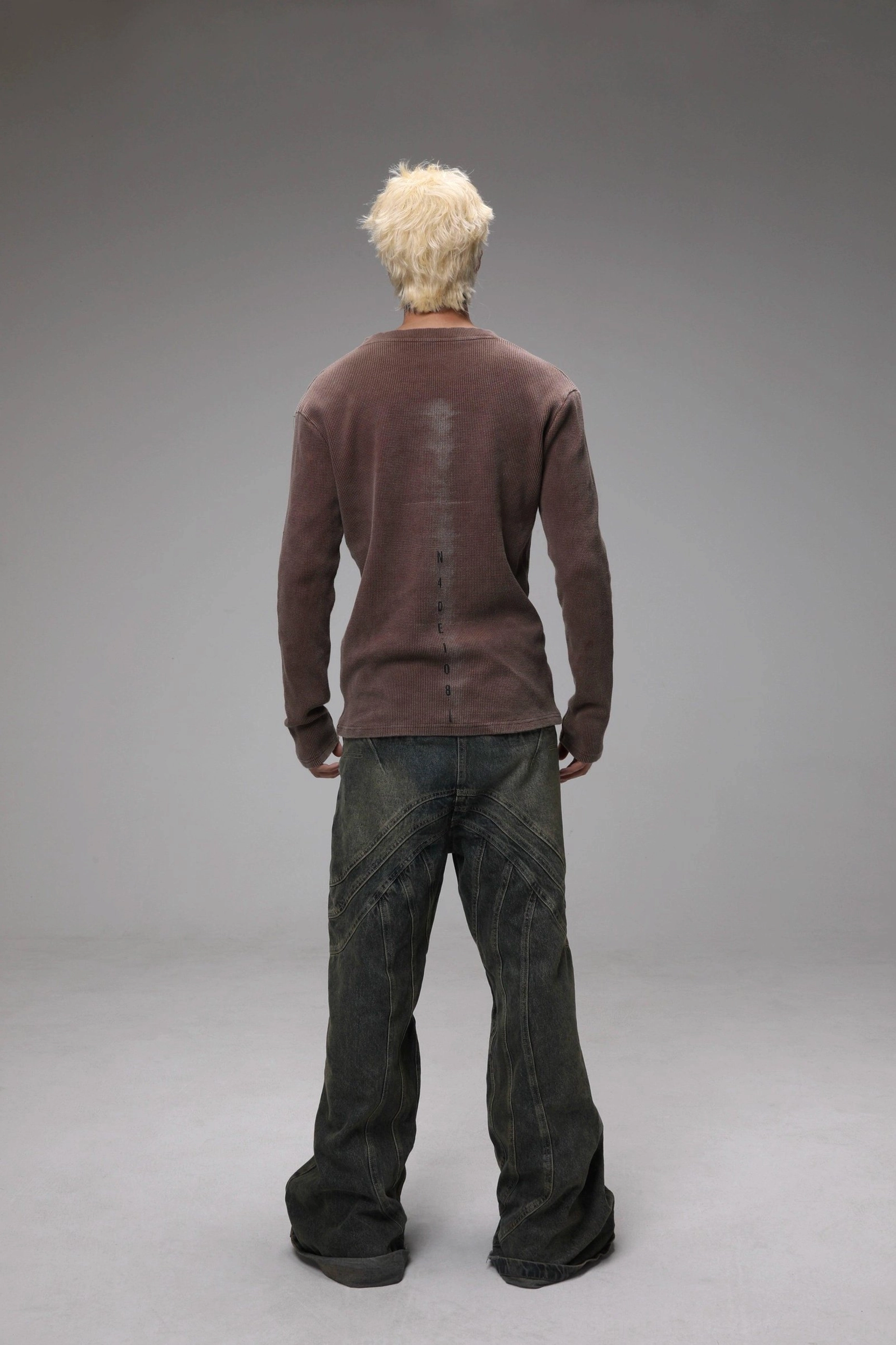 Rear view of maroon distressed knit Henley sweater styled with dark wide-leg jeans