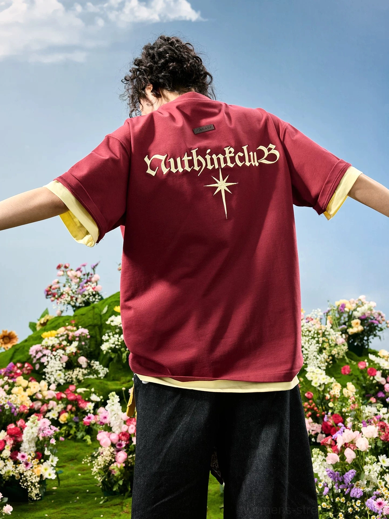 Maroon oversized embroidered back T-shirt on female model with arms extended, showing Gothic lettering and contrast faux two-piece construction