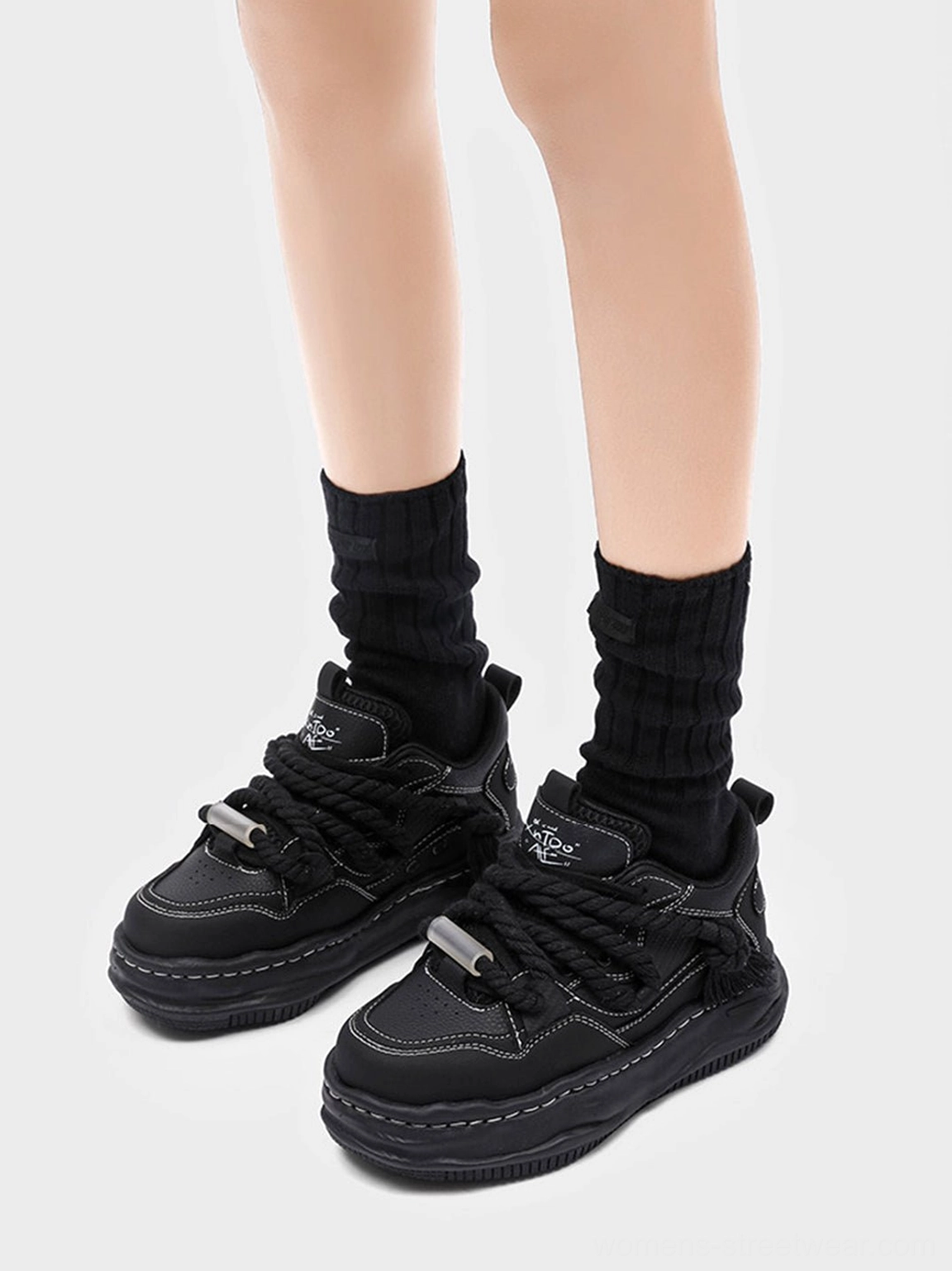 Matched pair of black wavy platform sneakers with thick elevated soles and rope-style laces