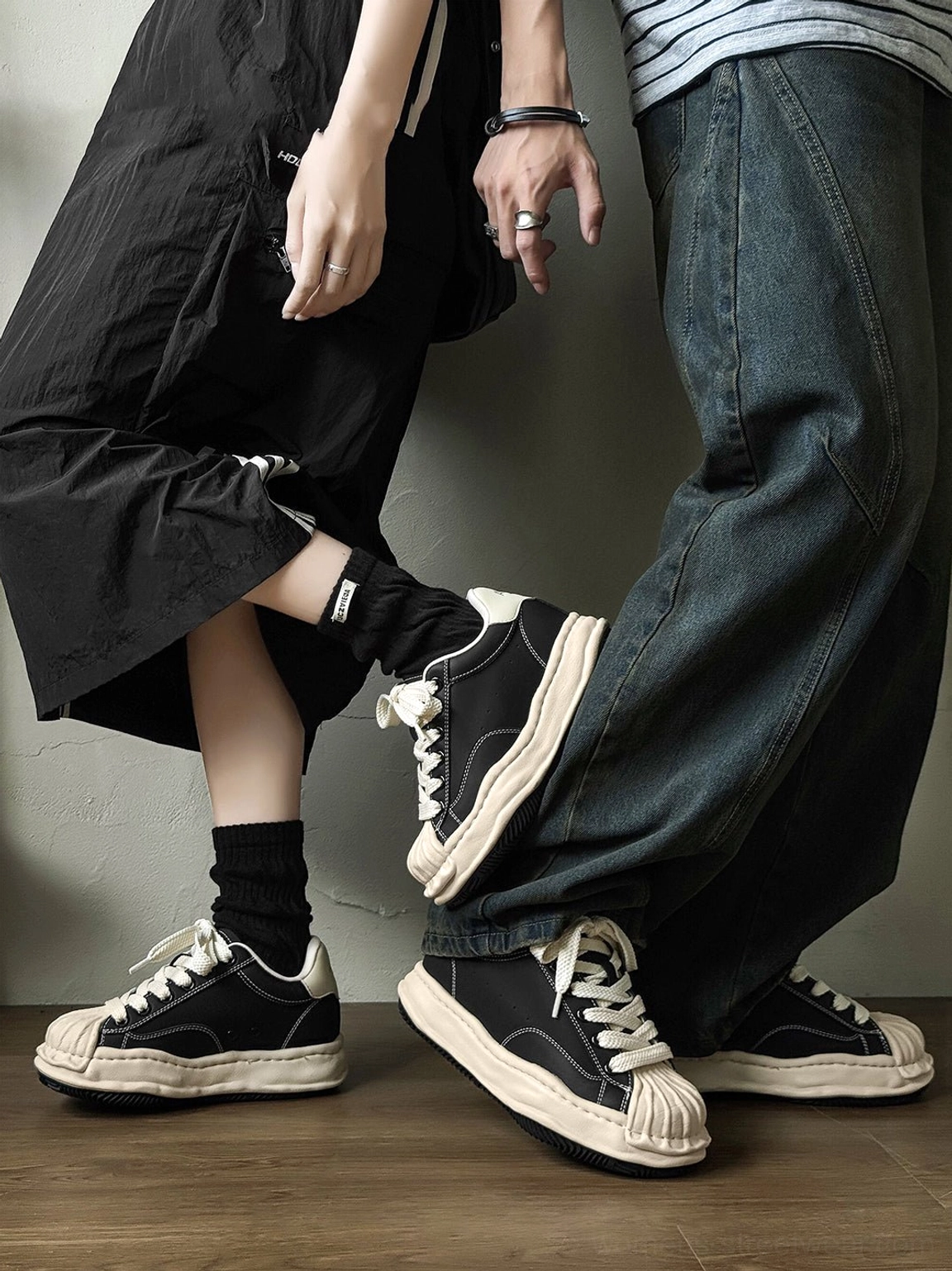 Two people wearing matching black and cream distressed platform court sneakers in a versatile casual streetwear styling view
