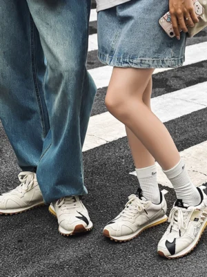 Matching ivory retro runner sneakers with black accents and gum waffle soles styled with denim outfits on an urban zebra crossing