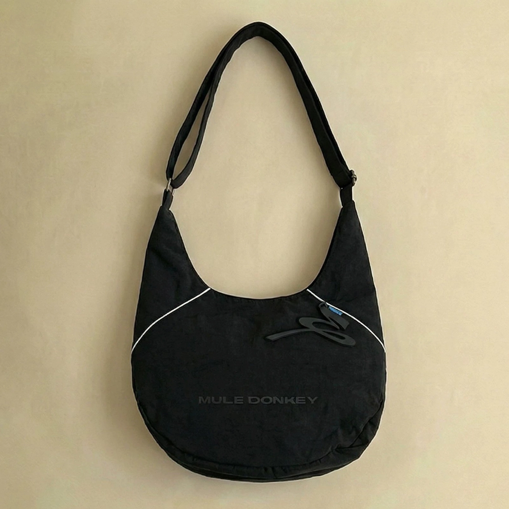 Matte black minimalist hobo shoulder bag with reflective edge piping soft nylon body and adjustable strap