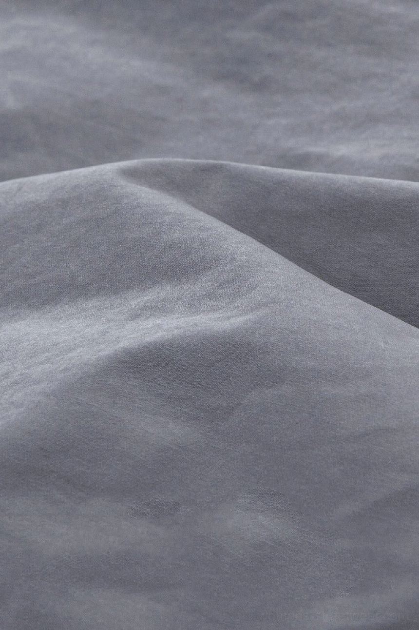 Close-up of smooth matte woven windbreaker fabric with soft drape and subtly water-resistant finish