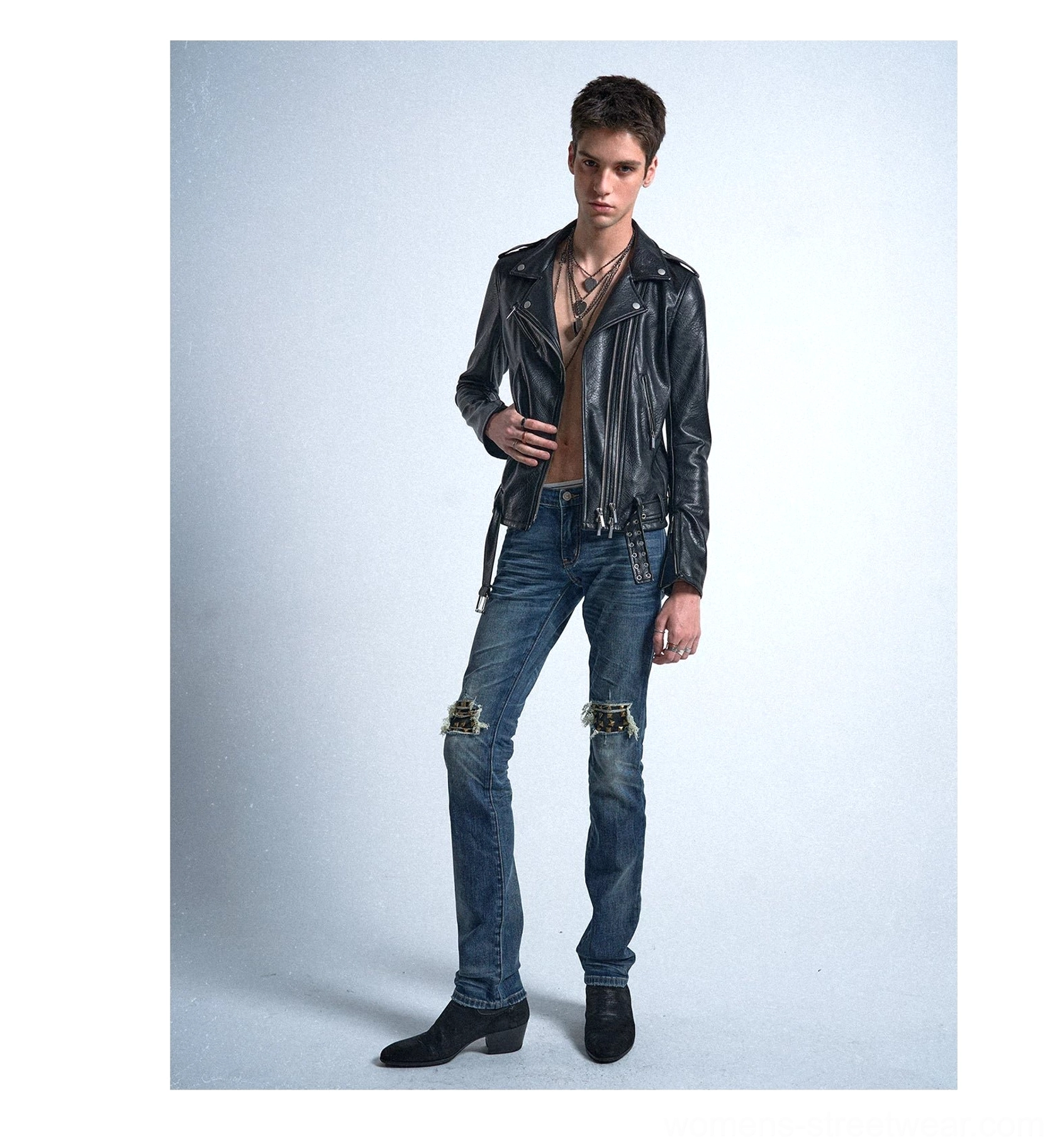 Front view of medium blue distressed knee-rip jeans styled with a black leather jacket for an alternative streetwear outfit