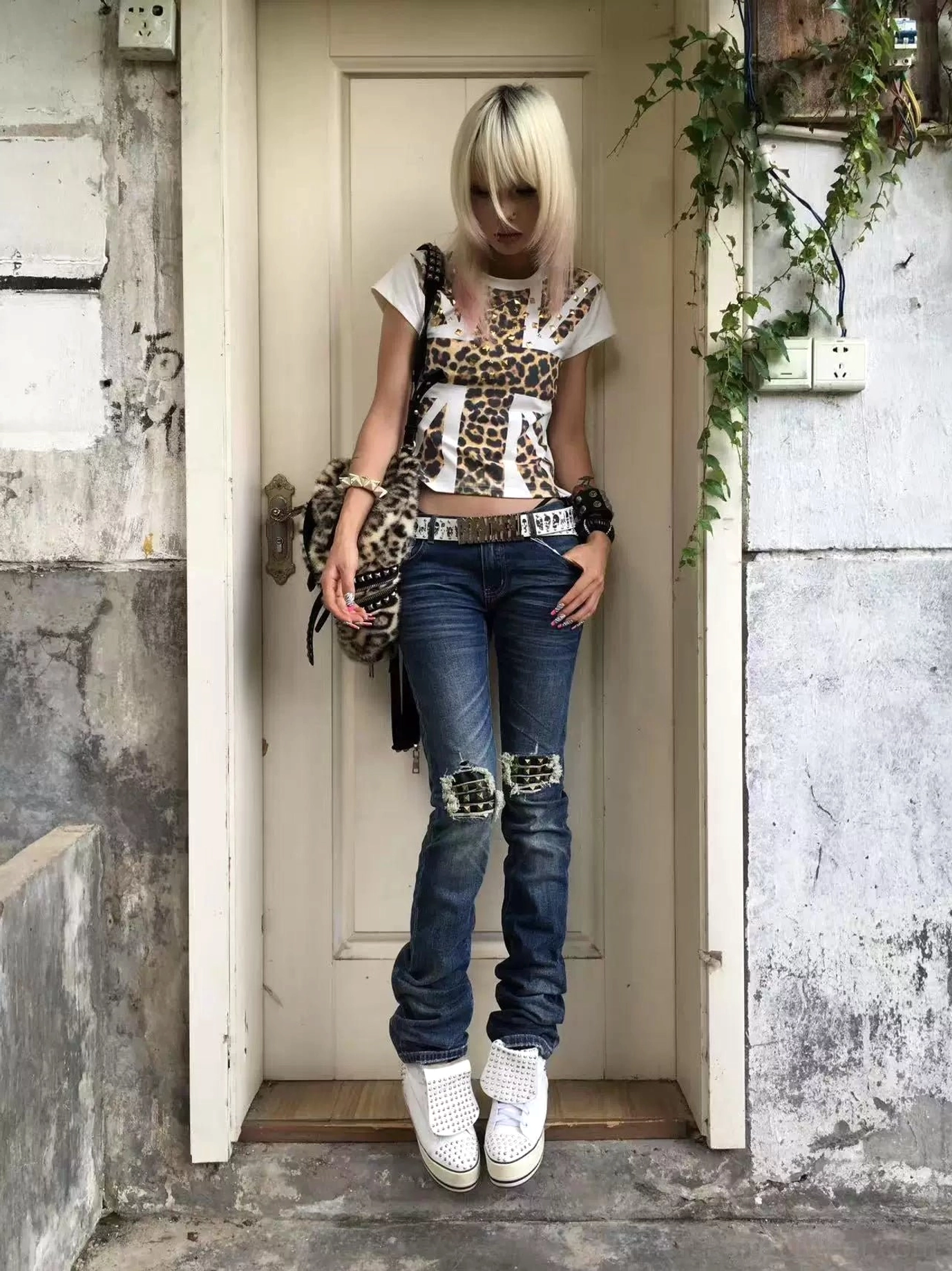 Front view of medium blue distressed slim jeans with rugged knee rips styled with a printed top and platform sneakers