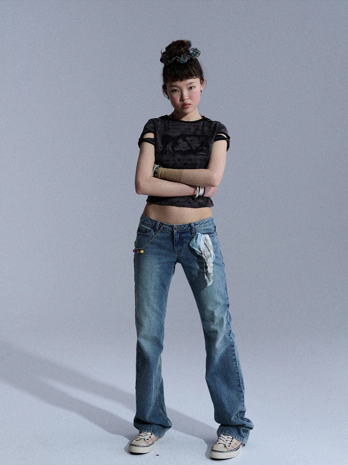 Full front view of medium blue vintage wash low-rise slim flare jeans with printed pocket accent and casual canvas shoes