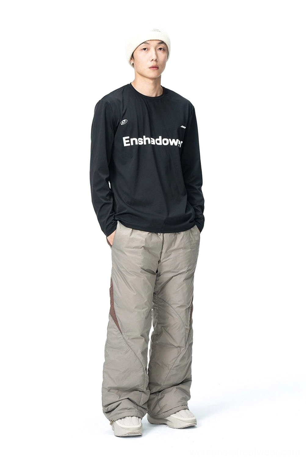 Male model styling spliced padded track pants with a white beanie graphic long-sleeve shirt and casual sneakers