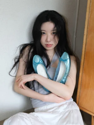 Asian woman wearing metallic blue quilted bow ballet flats with a white midi skirt in a modern Korean streetwear outfit