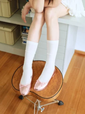 Metallic blush pink bow ballet flats styled with white ribbed mid calf socks in an overhead outfit view for coquette streetwear styling