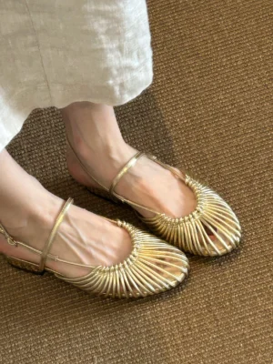 Metallic gold woven cage Mary Jane sandals shown from the side with slim ankle strap and low block heel