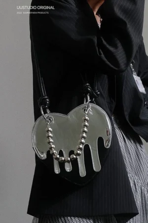 Side view of metallic silver heart crossbody mini bag styled with a black pinstripe blazer and checkered skirt