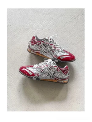 Angled overhead view of red silver retro mesh racing sneakers with breathable mesh panels metallic overlays and low-top streetwear silhouette