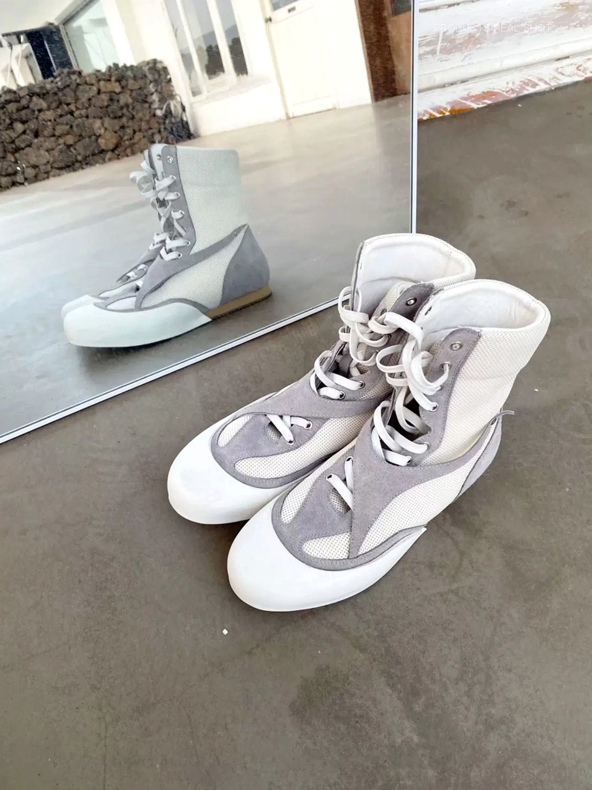 White and grey metallic mesh high-top boxing boots beside mirror reflection highlighting the mixed-material side profile