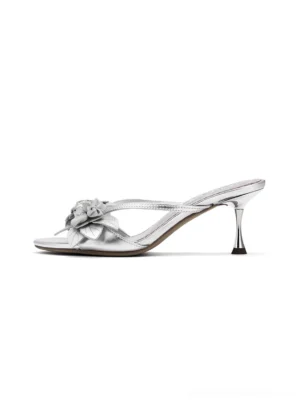 Metallic silver floral kitten heel slide sandals shown from the right side with an open toe, decorative flower detail, slim straps, and elegant tapered heel