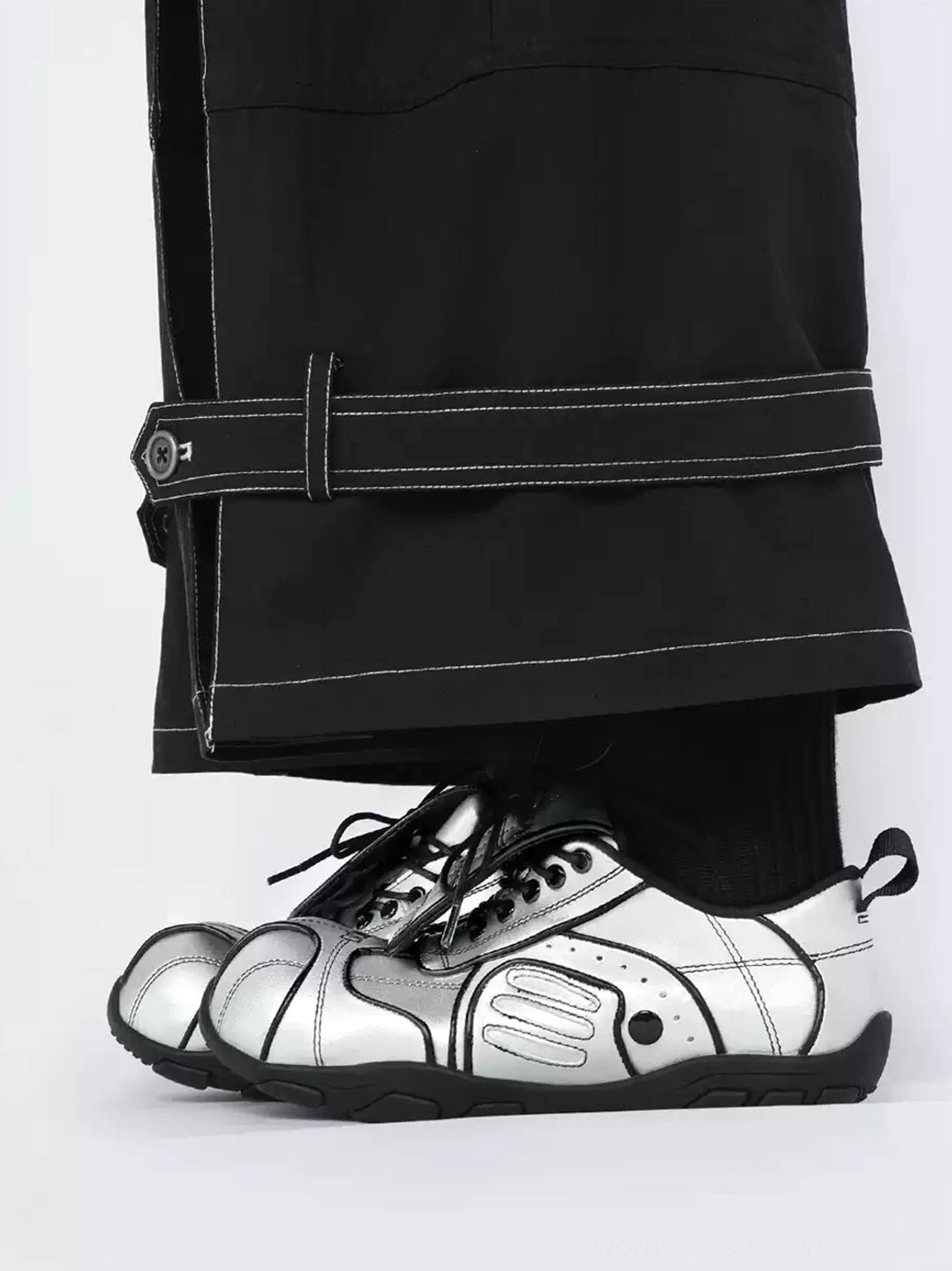 Left-side view of metallic silver foldover-tongue sneakers worn with black cargo pants, showing quilted toe panels and black heel pull tab