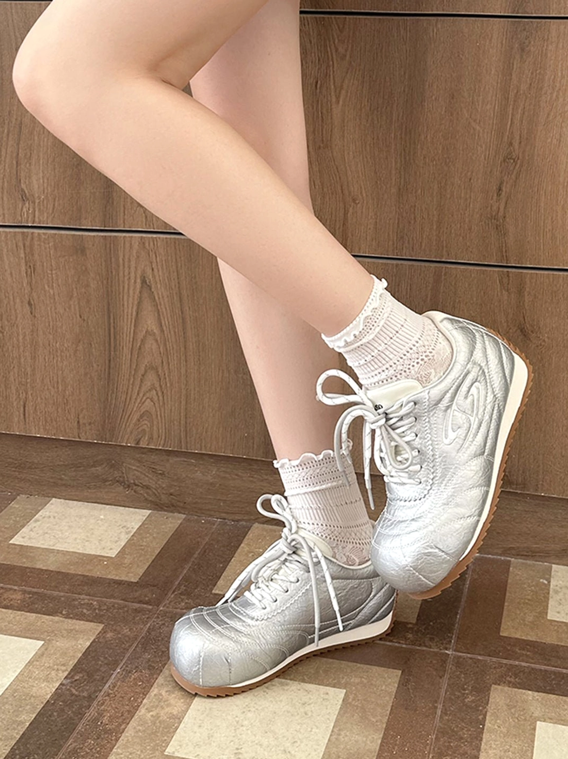 Metallic silver low-profile retro trainers worn with white frilled socks for a Seoul streetwear inspired outfit