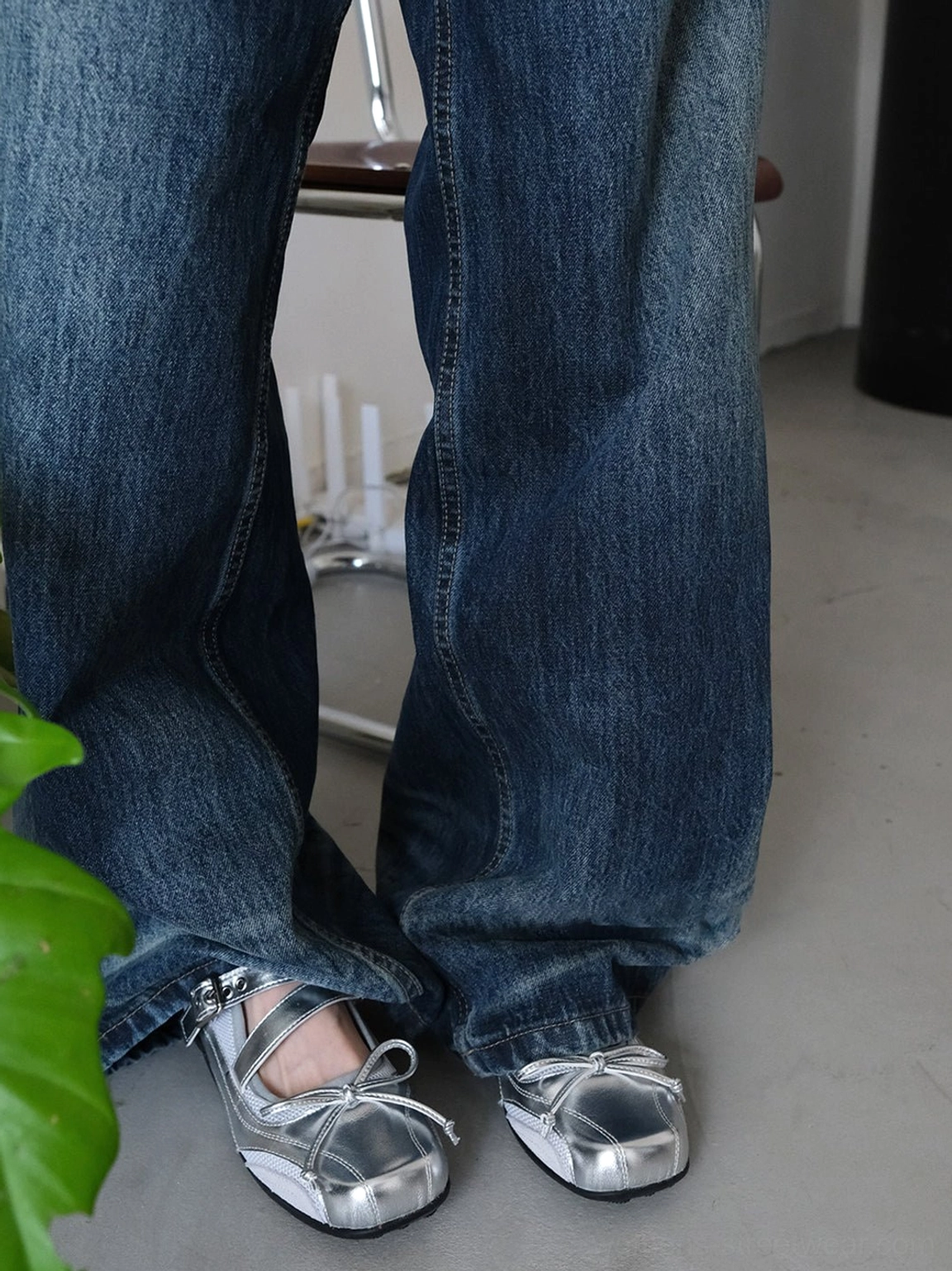 Metallic silver Mary Jane flats with toe bows and adjustable straps shown with wide-leg jeans
