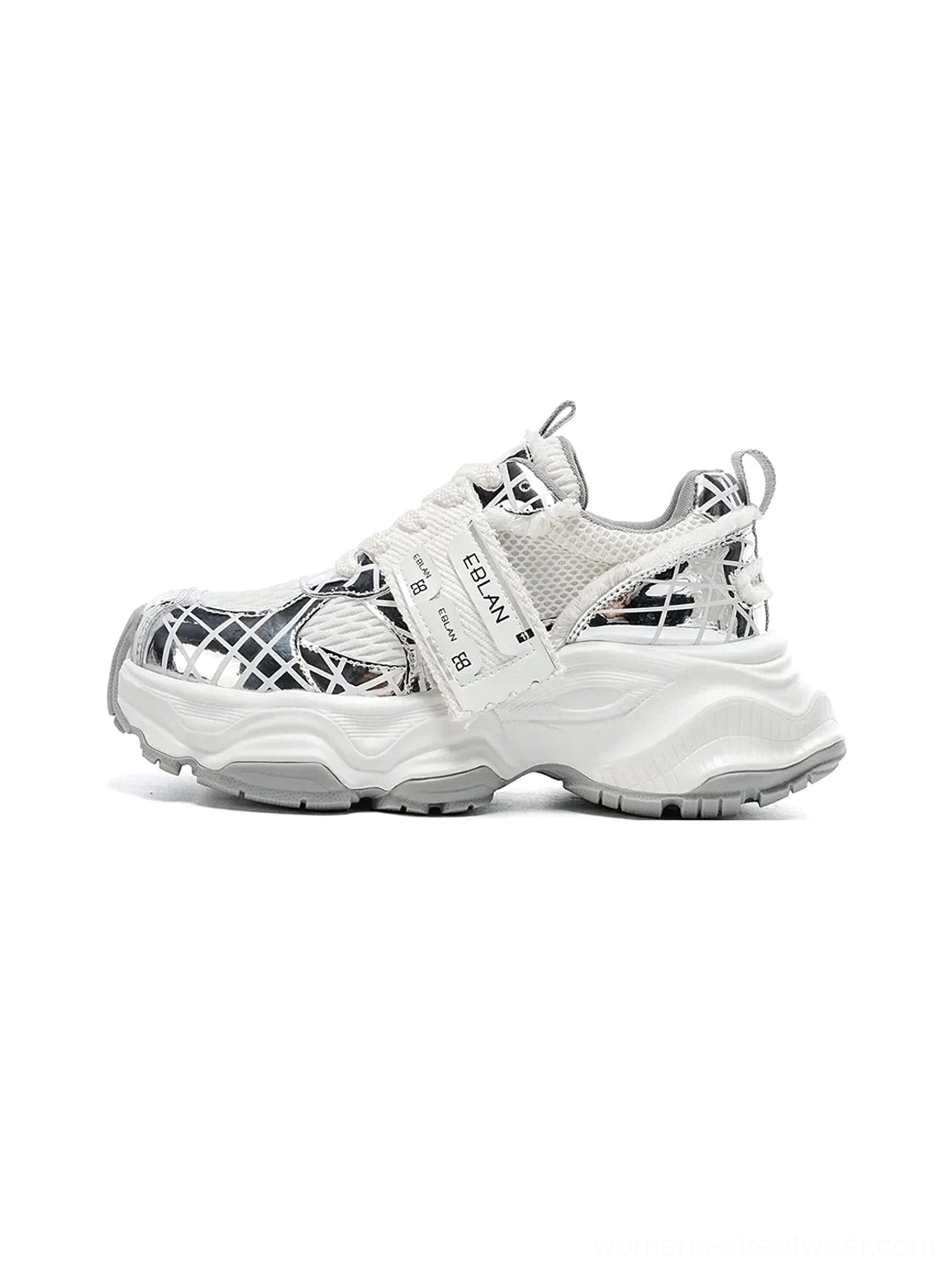 Metallic silver mesh tech runner sneaker in a left front three-quarter view with chunky sculpted outsole, breathable grid upper, reflective overlays, lace-up closure, and adjustable strap