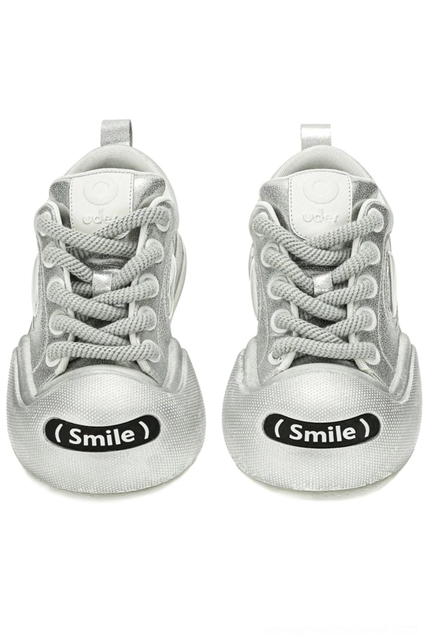 Front view of matching metallic silver platform canvas sneakers with rounded oversized toes, thick woven laces, and playful toe details