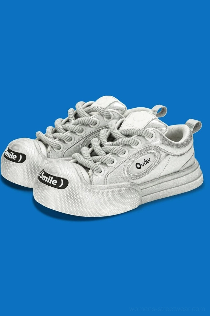 Three-quarter view of metallic silver platform canvas sneakers with reflective upper, side patches, rounded toe caps, and chunky streetwear soles