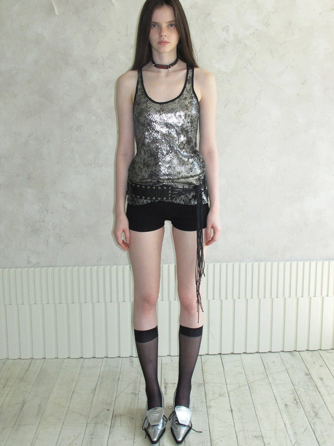 Front view of metallic silver pointed-toe pumps styled with black shorts sheer stockings and sequined top
