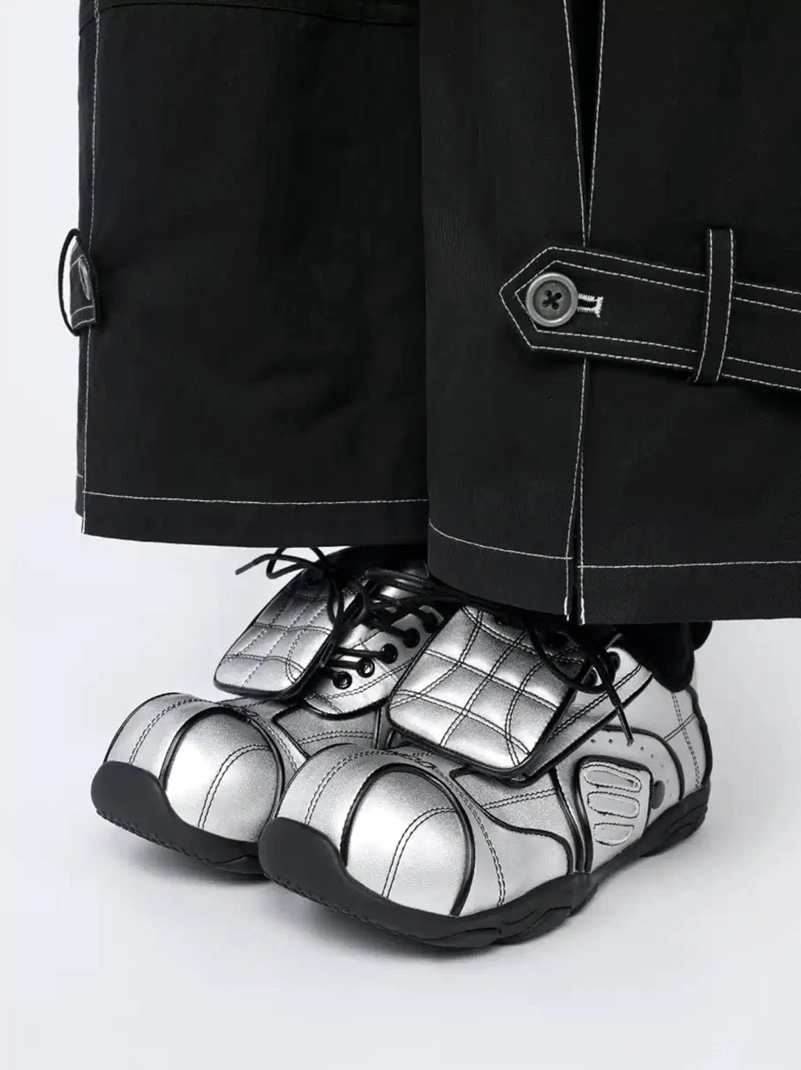 High-angle view of metallic silver quilted foldover-tongue sneakers styled with black contrast-stitch cargo pants and black socks