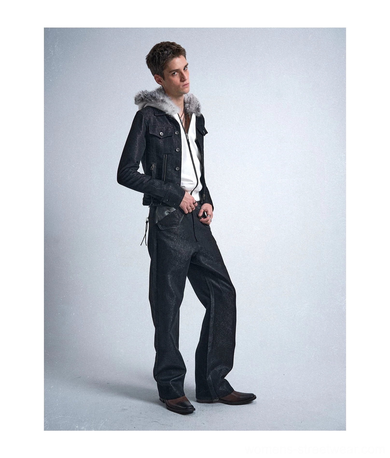 Side view of loose black metallic raw straight jeans paired with a fur collar jacket and white top