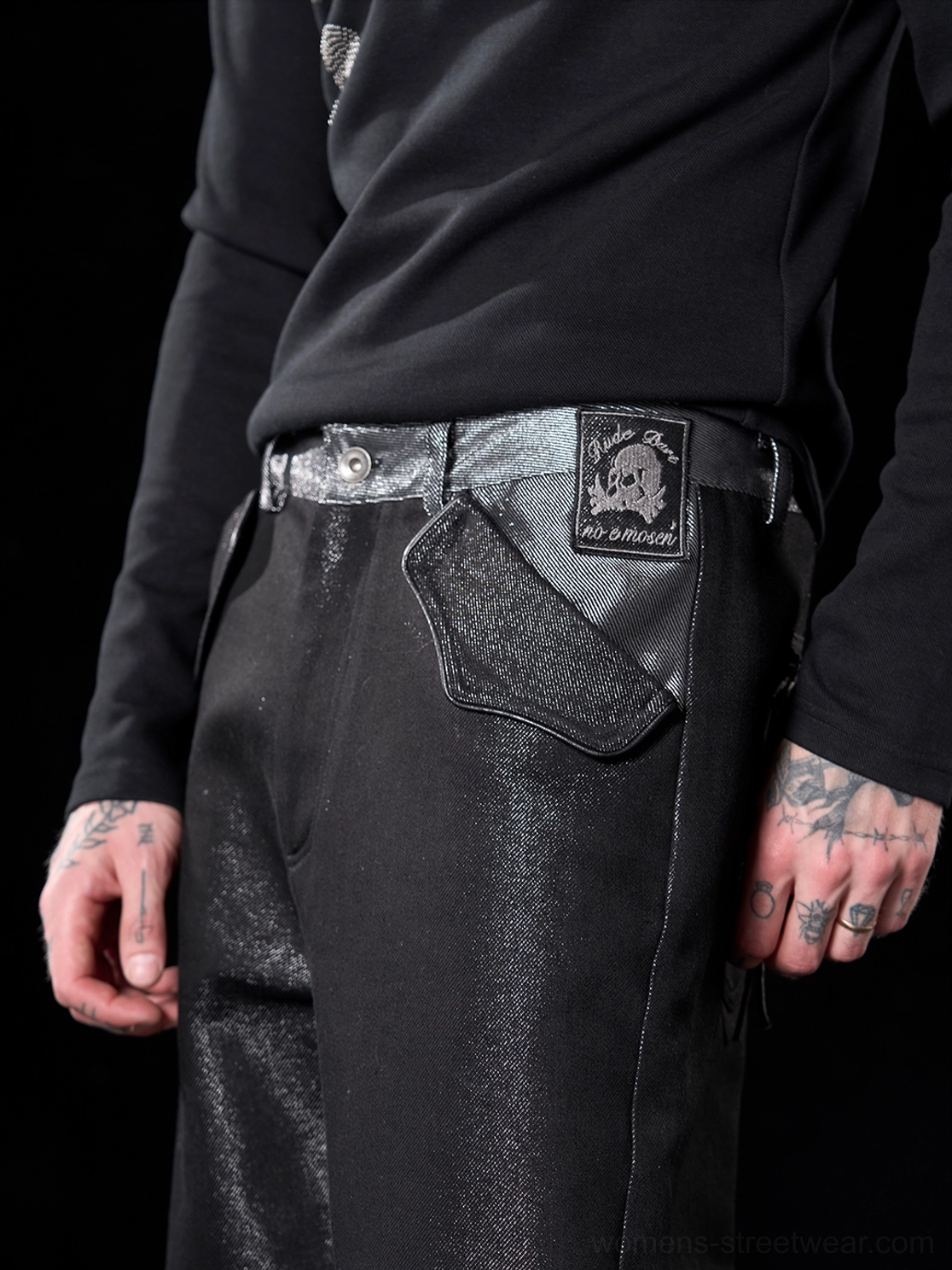 Close-up of metallic black raw jeans waistband with skull patch silver contrast trim and shaped front pocket