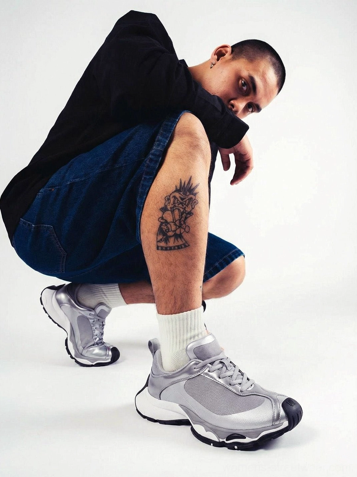 Metallic split-toe technical runner sneaker worn with white crew socks, black top, and denim shorts in a futuristic streetwear outfit