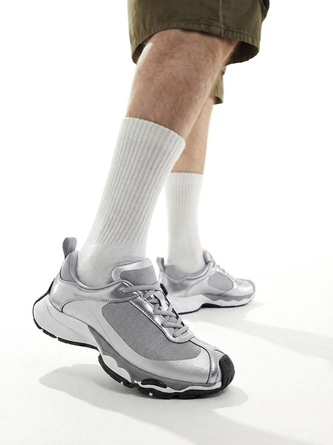 Metallic split-toe technical runner sneaker worn from a rear side angle, showing the layered upper, heel structure, and sculpted chunky outsole