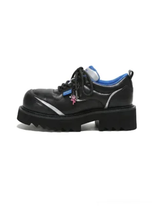 Black chunky lug-sole derby shoes with metallic silver side trim, blue lining, lace charms, and deep tread platform outsole on a white background
