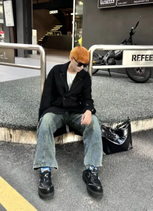 Chunky platform derby shoes styled with casual streetwear on a male model at an outdoor cafe, showing the bold black lug sole and metallic trim
