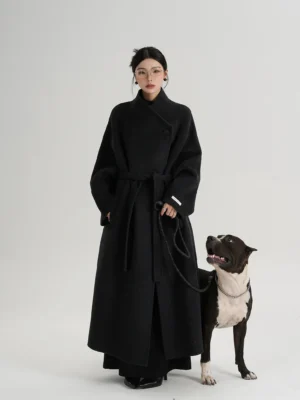 Mid-length dark gray wool blend wrap coat with asymmetric collar, removable waist belt, side pockets, soft fuzzy fabric, wide leg trousers, and black leather loafers