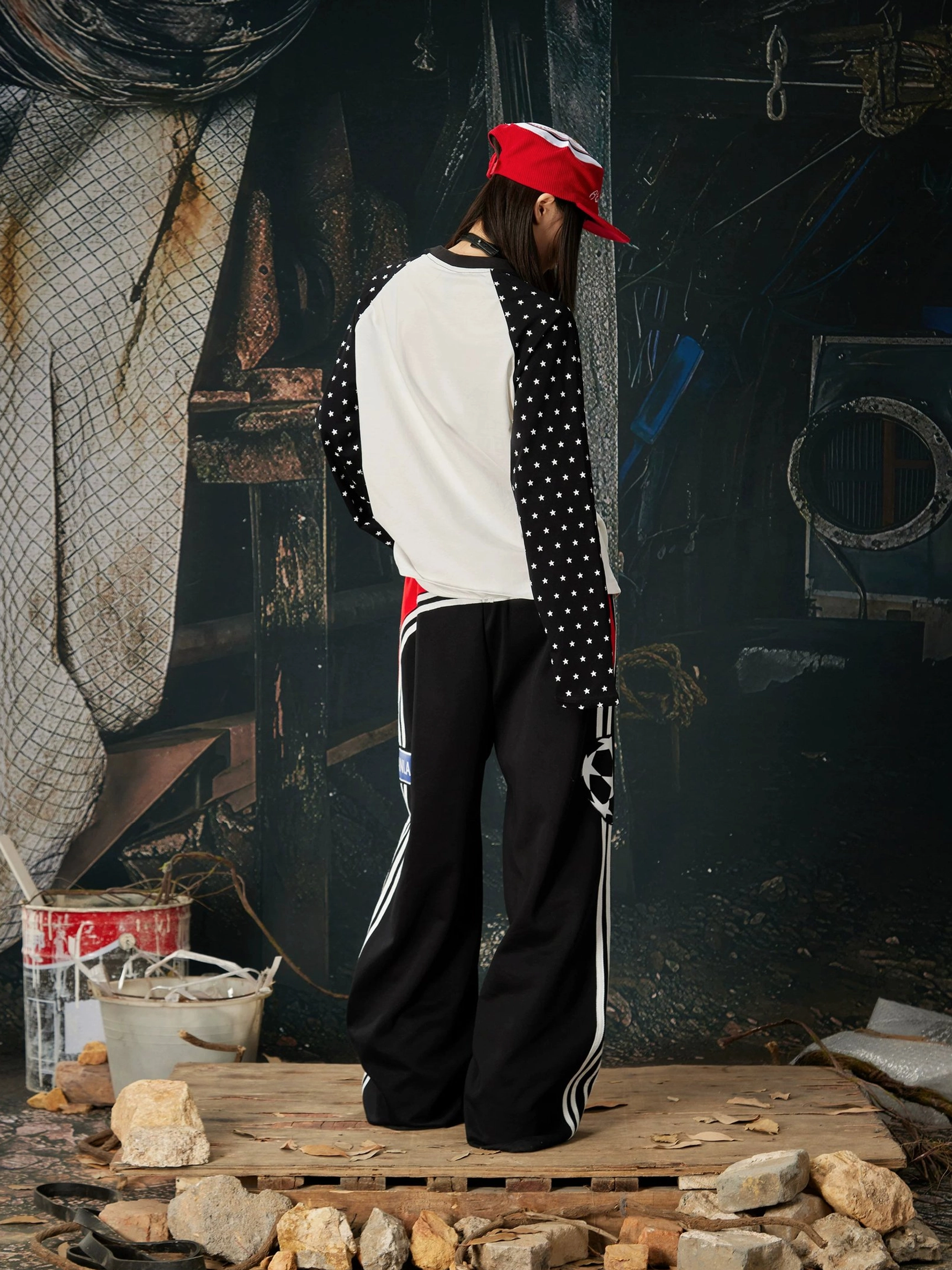 Side rear view of black 1998 graphic streetwear sweatpants with relaxed wide-leg fit, red waistband detail, and sporty stripes