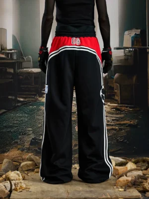 Rear view of black wide-leg streetwear sweatpants with contrast waist panel, number graphic, white side stripes, and oversized relaxed fit