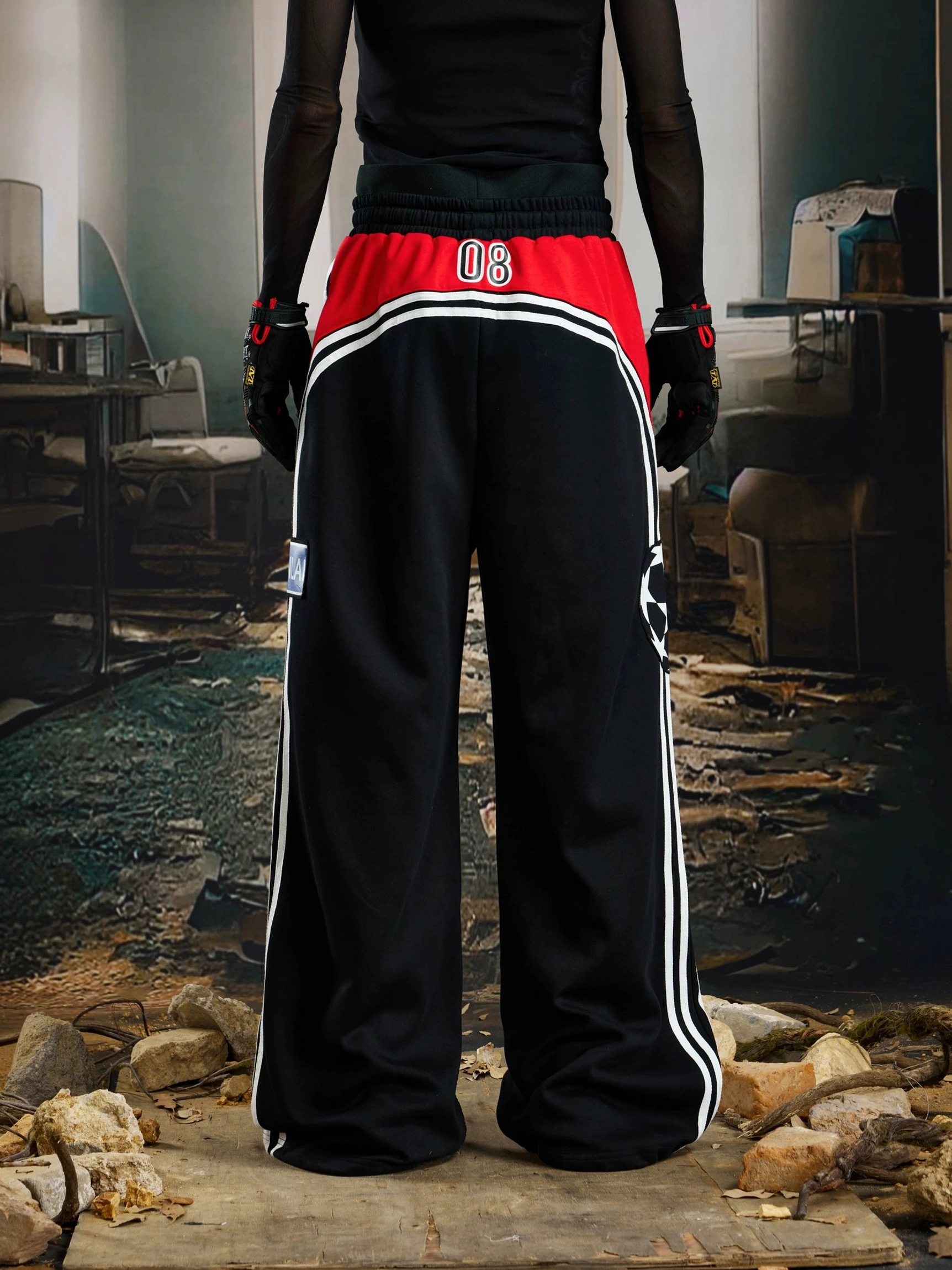 Rear view of black wide-leg streetwear sweatpants with contrast waist panel, number graphic, white side stripes, and oversized relaxed fit