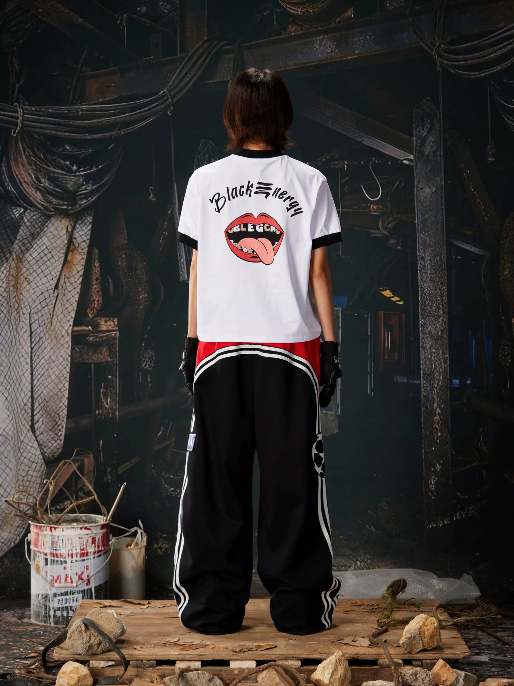 Rear outfit view featuring black wide-leg 1998 graphic sweatpants with red waist panel, white stripes, and coordinated graphic top
