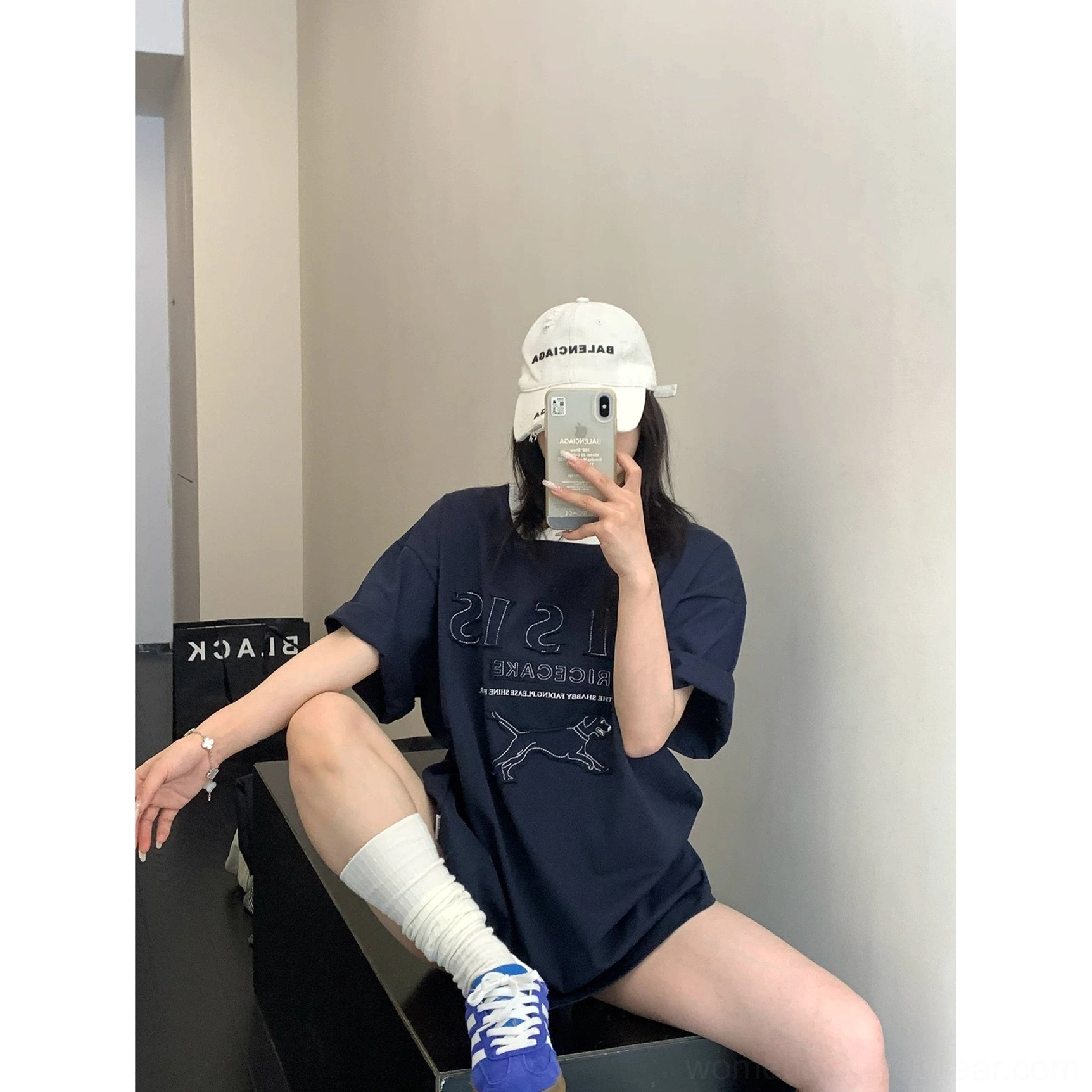 Side view of navy blue oversized cotton graphic tee styled with white socks and blue sport sneakers