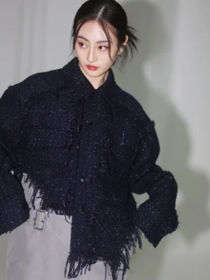 Three-quarter front view of a midnight navy oversized fringe tweed jacket with textured bouclé fabric, sparkling woven sheen, shirt collar, and raw distressed hem