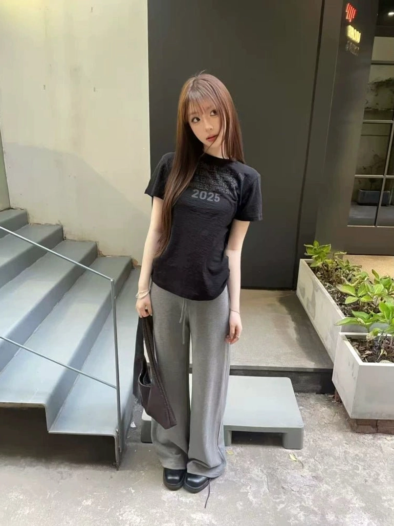 Black Midnight Outcome 2025 graphic tee styled with gray wide-leg trousers in a modern Seoul streetwear outfit