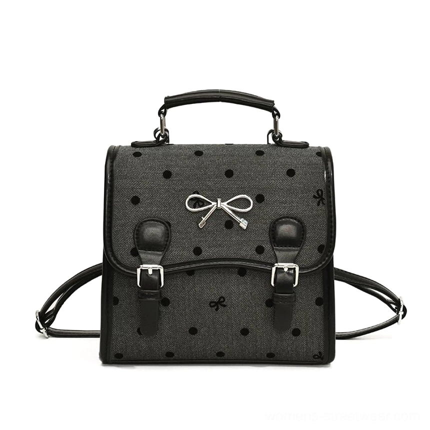 Midnight polka bow sweet academy satchel backpack in dark grey with black polka dots, bow print, black faux leather trim and silver buckle hardware front view