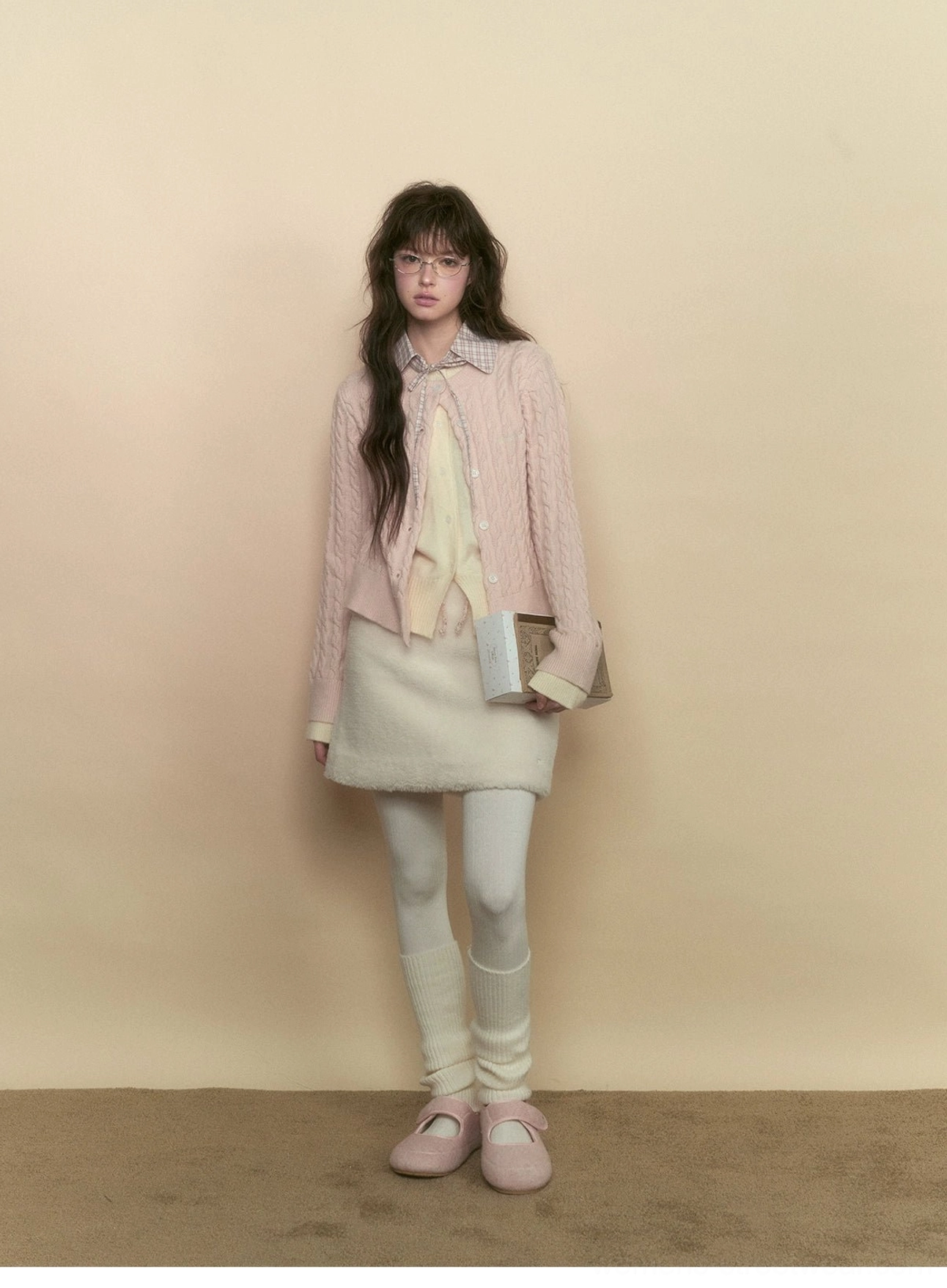 Full body view of milky pink cable knit preppy cardigan with an ivory mini skirt in a soft academia outfit