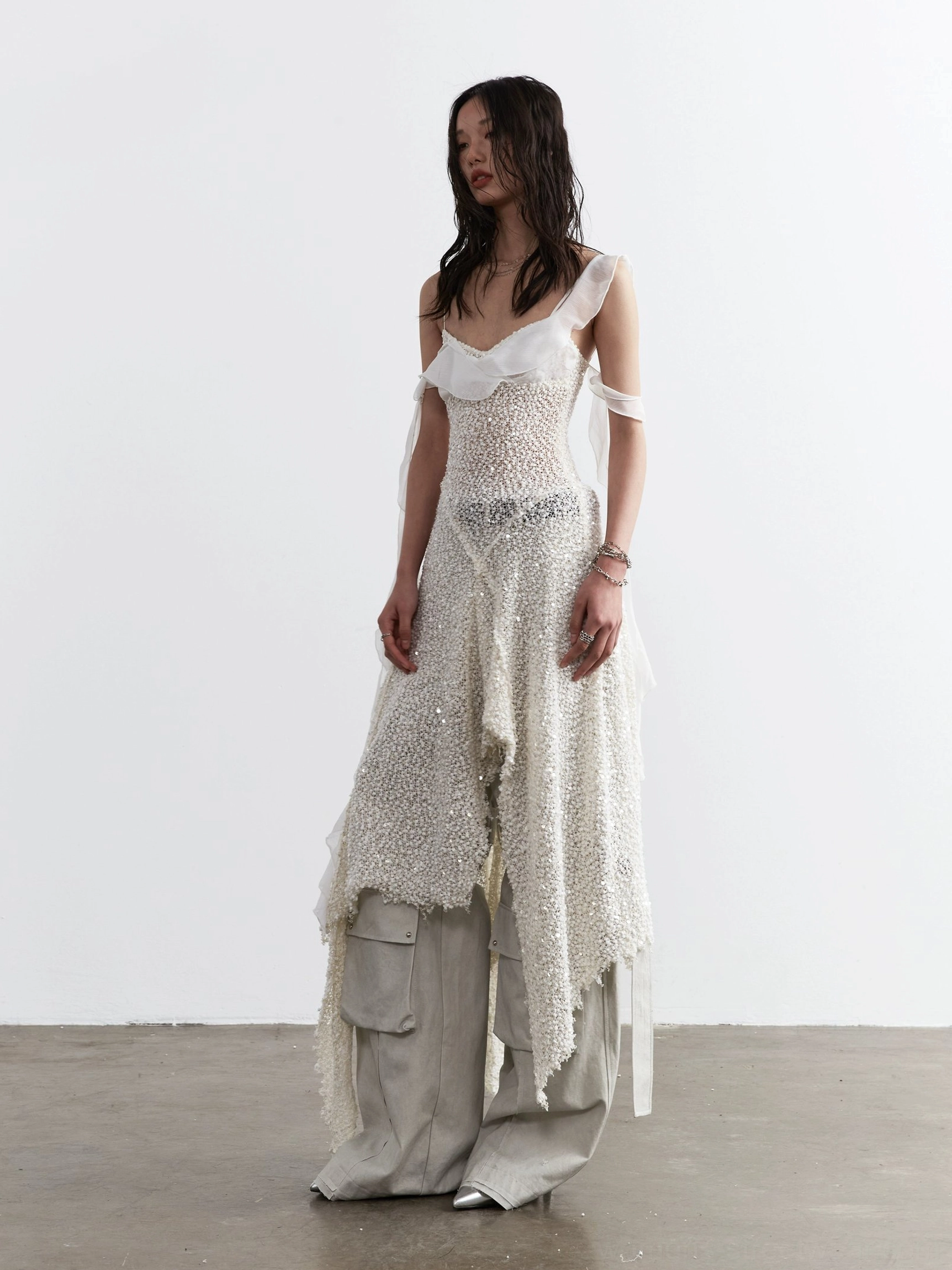 Side three quarter view of milky white sequin mesh asymmetric dress paired with light grey cargo pants