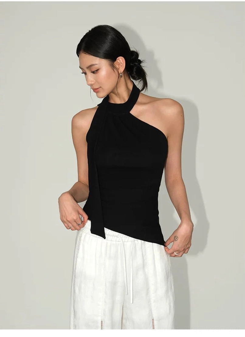 Minimalist asymmetric halter tank top with curved hem, smooth knit texture, and versatile day-to-night styling