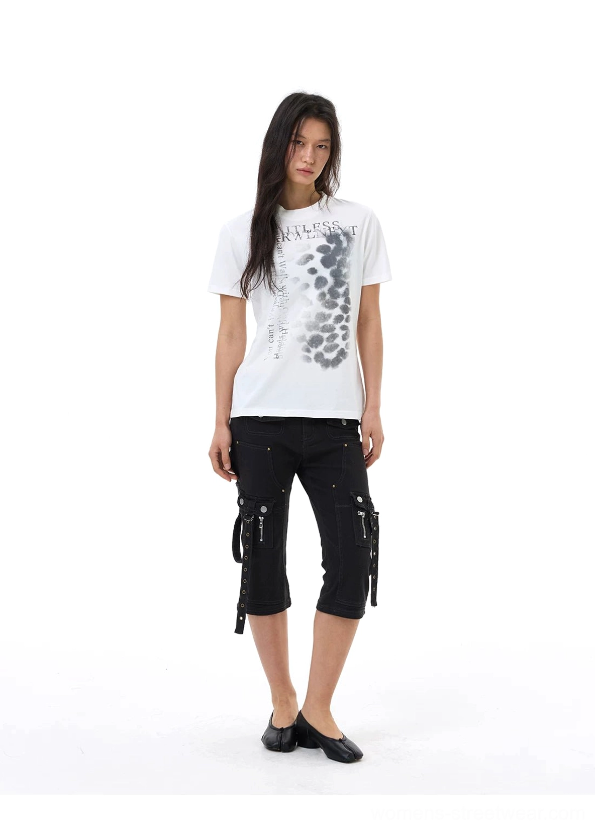 Front view of minimalist black cargo capri jeans with slim cropped legs, side zipper strap pockets, and dark monochrome streetwear styling