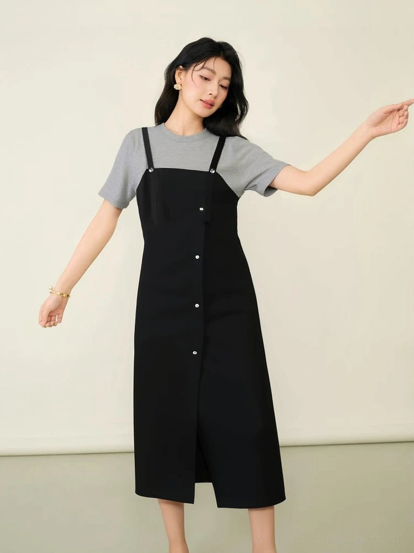 Full front view of a minimalist black pinafore midi dress with grey short-sleeve tee, adjustable straps, and practical side split