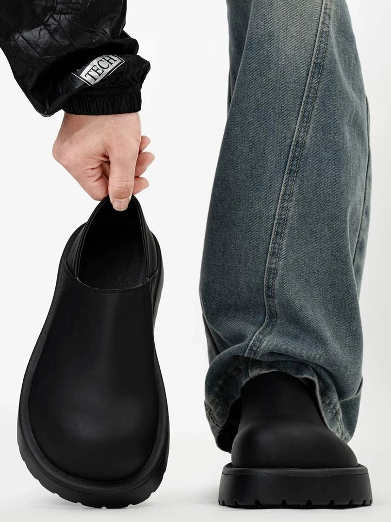 Front view of matte black rounded-toe platform slip-on clogs styled with relaxed blue jeans