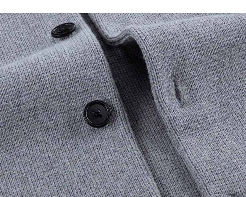 Close-up detail of functional dark buttons and buttonholes on ash gray minimalist wool blend cardigan